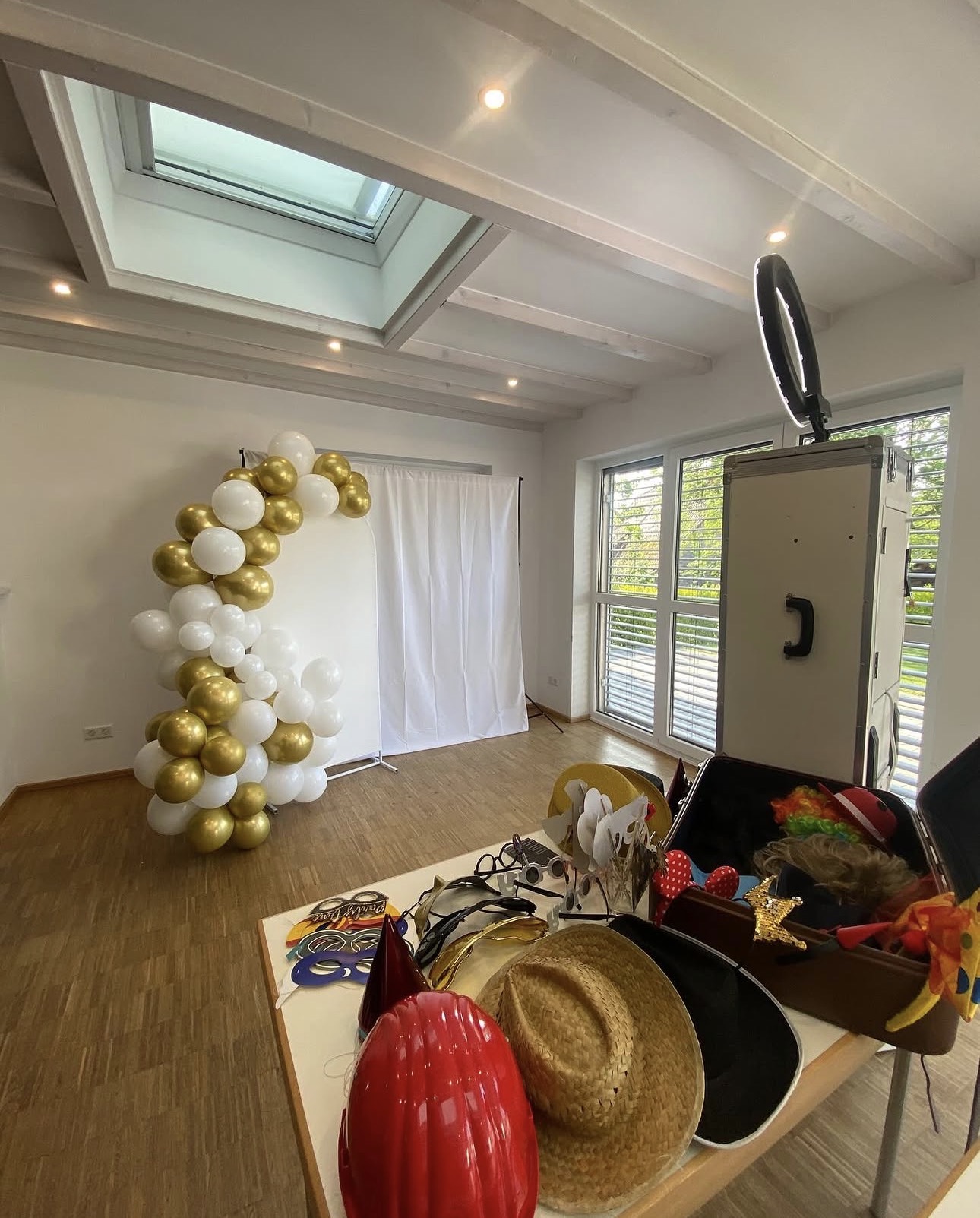 Gold-weiße Ballongirlande mit Fotobox und Requisiten