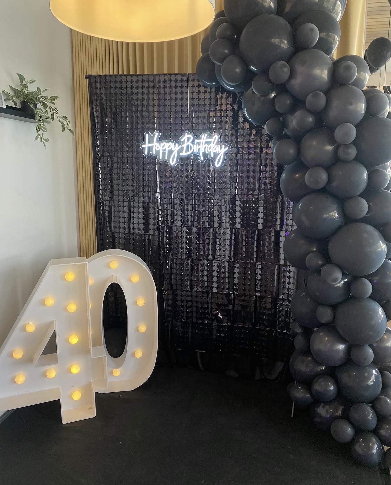 Schwarze Ballongirlande an Pailettenwand mit Leuchtzahl 40